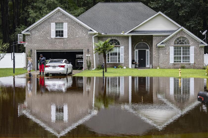 Keon Johnson and his wife Zyla Johnson, left, talk about how to get to work since his house on Tappan Zee Drive that was flooded on Monday from Tropical Storm Debby, Wednesday, Aug. 7, 2024, in Pooler, Ga. (AP Photo/Stephen B. Morton)