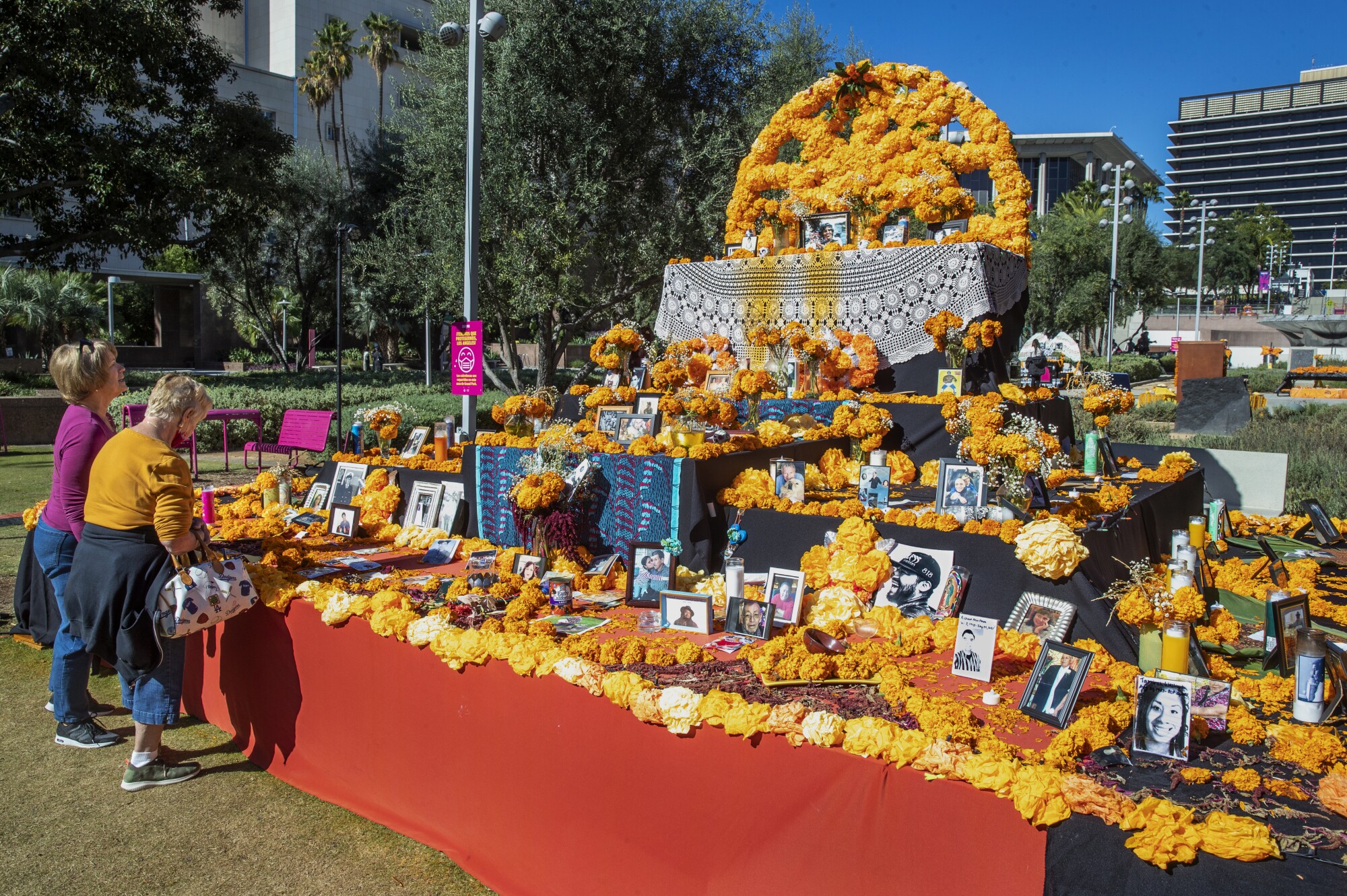 Two women look up at the community altar at Grand Park in Los Angeles.