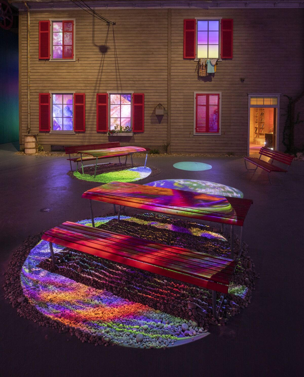 Colorful video projections sweep across the facade of a house and its yard.