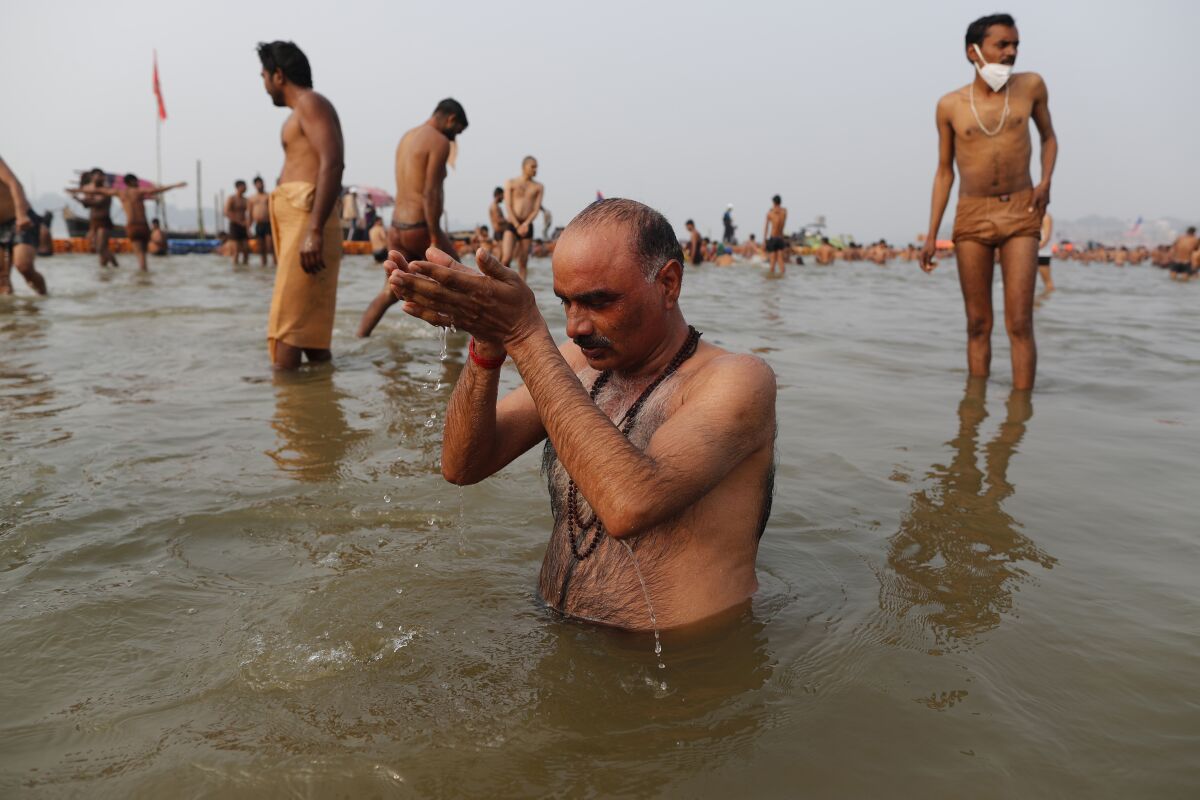 Hindu devotees take ritualistic dips in the Sangam, the confluence of three rivers — the Ganges, the Yamuna and the mythical Saraswati, during Makar Sankranti festival that falls during the annual traditional fair of Magh Mela festival, one of the most sacred pilgrimages in Hinduism, in Prayagraj, India. Friday, Jan. 14, 2022. Tens of thousands of devout Hindus, led by heads of monasteries and ash-smeared ascetics, took a holy dip into the frigid waters on Friday despite rising COVID-19 infections in the country. (AP Photo/Rajesh Kumar Singh)