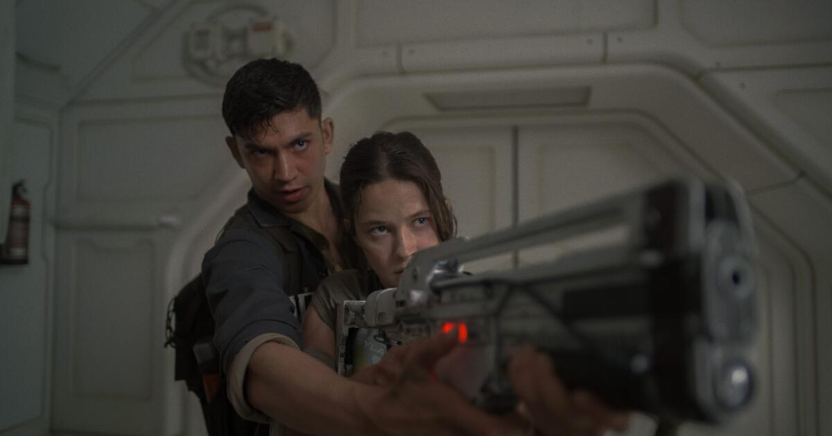 Archie Renaux's character Tyler shows Cailee Spaeny's Rain how to use a futuristic weapon.