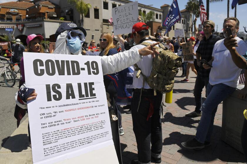 Protesters, including anti-vaccine activists, demonstrate against stay-at-home orders that were put in place due to the COVID-19 outbreak, Friday, April 17, 2020, in Huntington Beach, Calif.