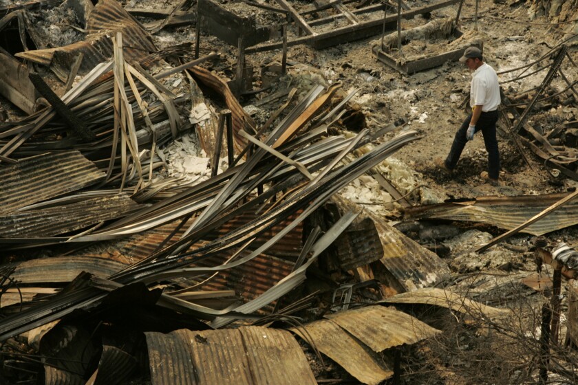 An employee with Malibu Glass & Mirror walks through the rubble of the business after the October 2007 Malibu Canyon fire.