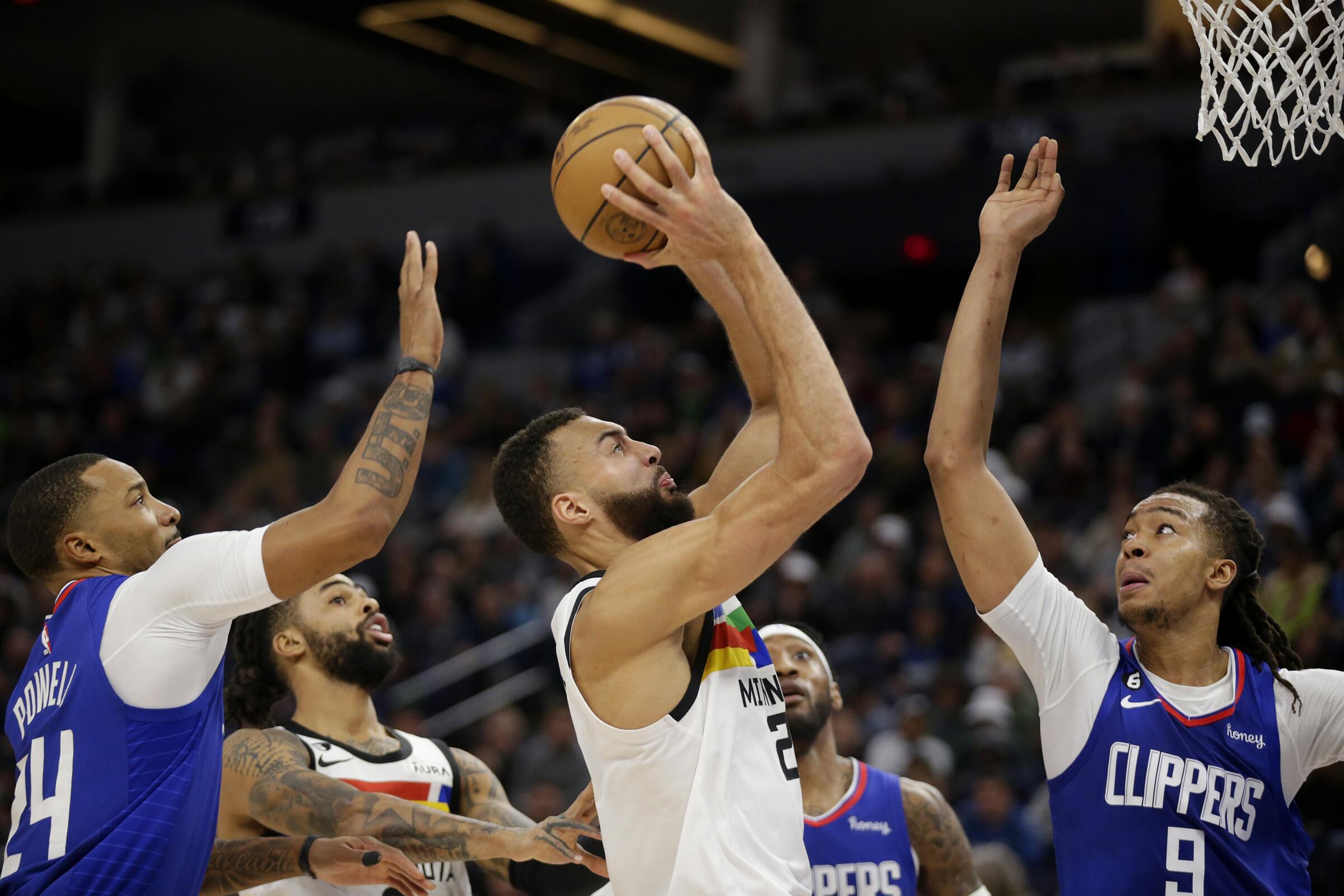 Timberwolves center Rudy Gobert shoots between the Clippers' Norman Powell (24) and Moses Brown (9) on Jan. 6, 2023.