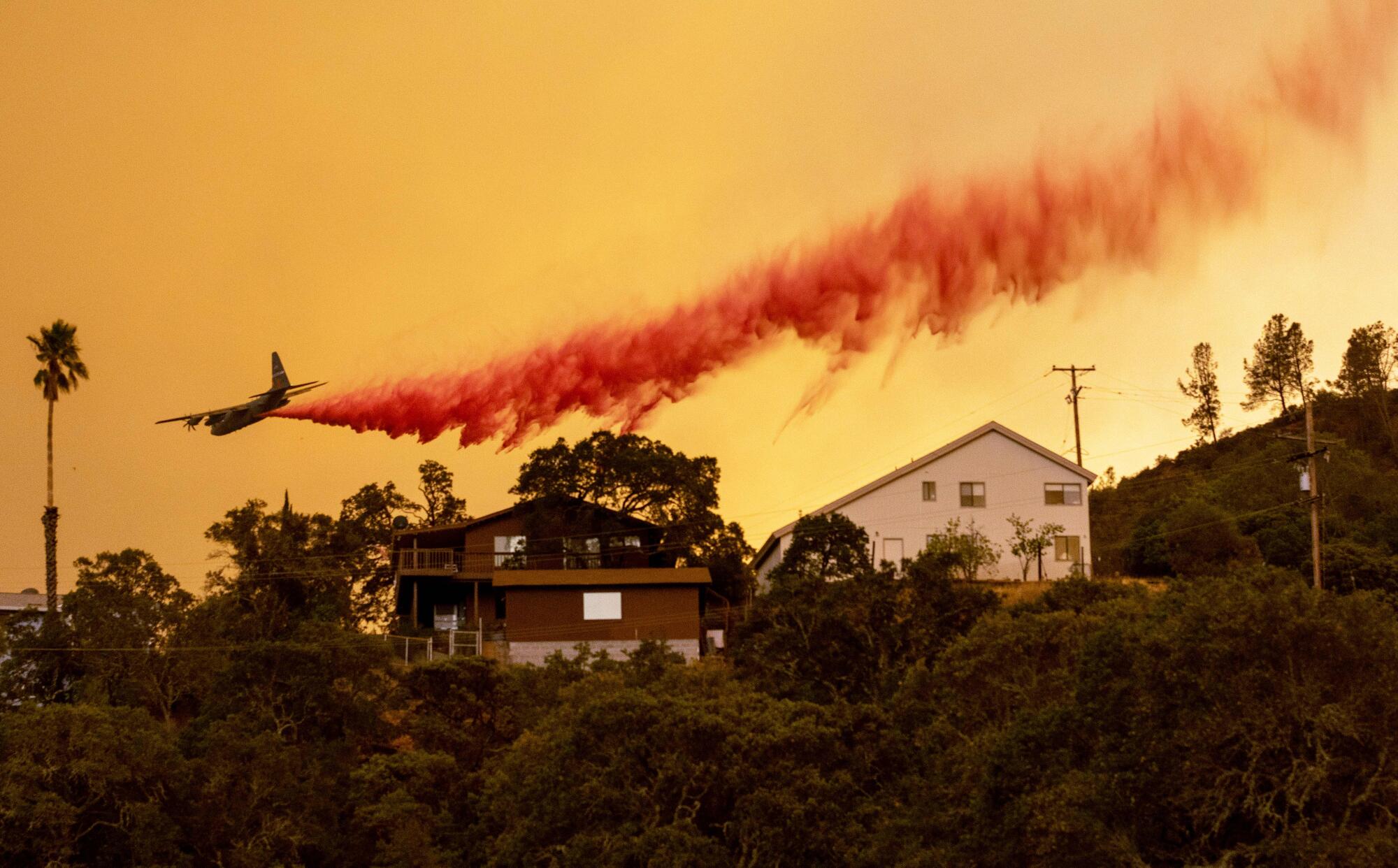 An airplane drops fire retardant over homes in Napa County.