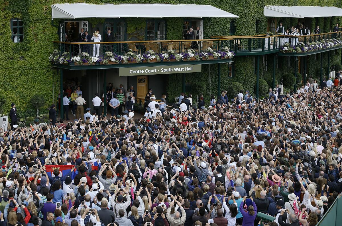 Novak Djokovic kisses the trophy on the balcony of Centre Court in July 2015.