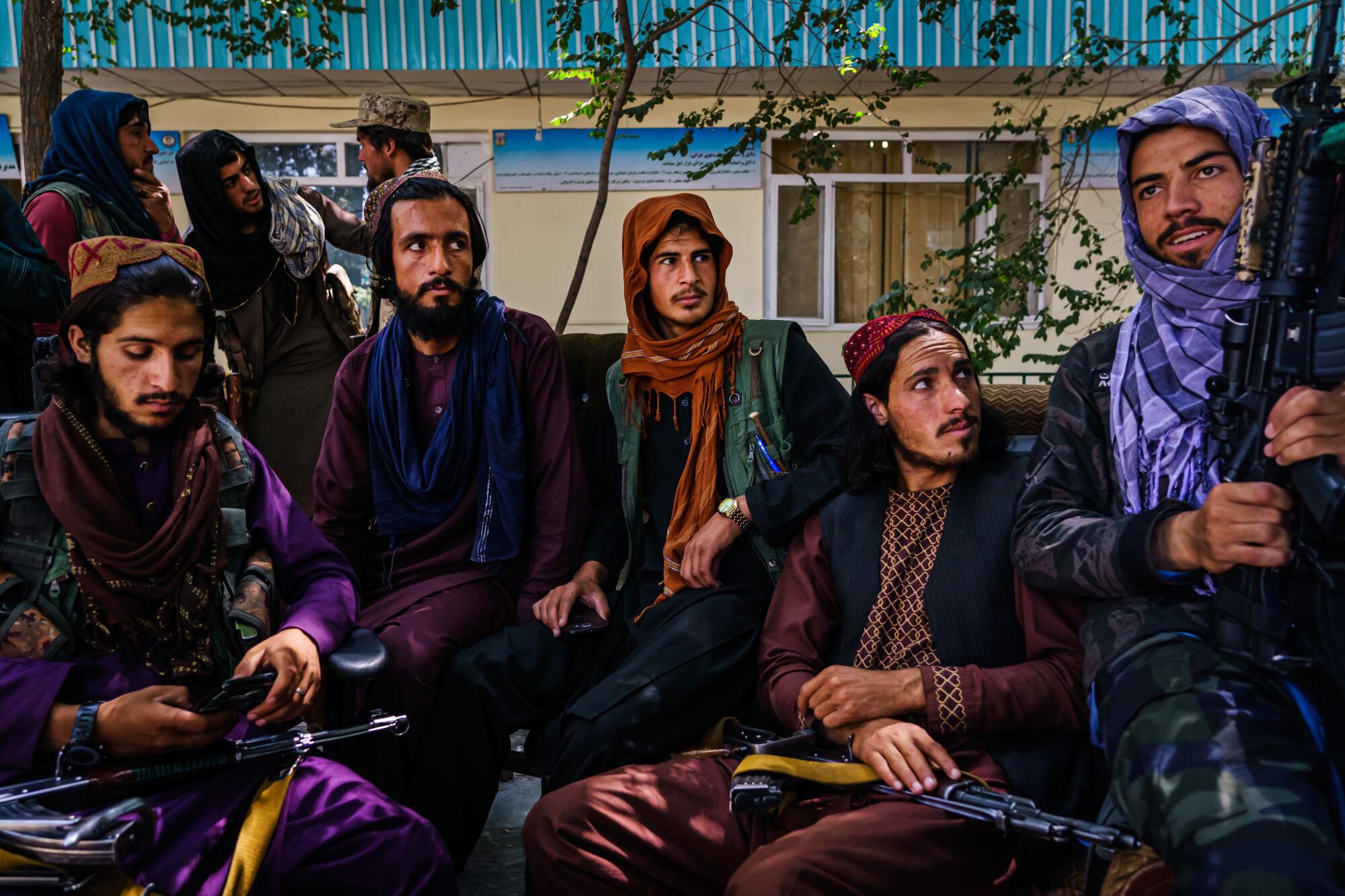 Men in scarves and caps sit, holding guns.