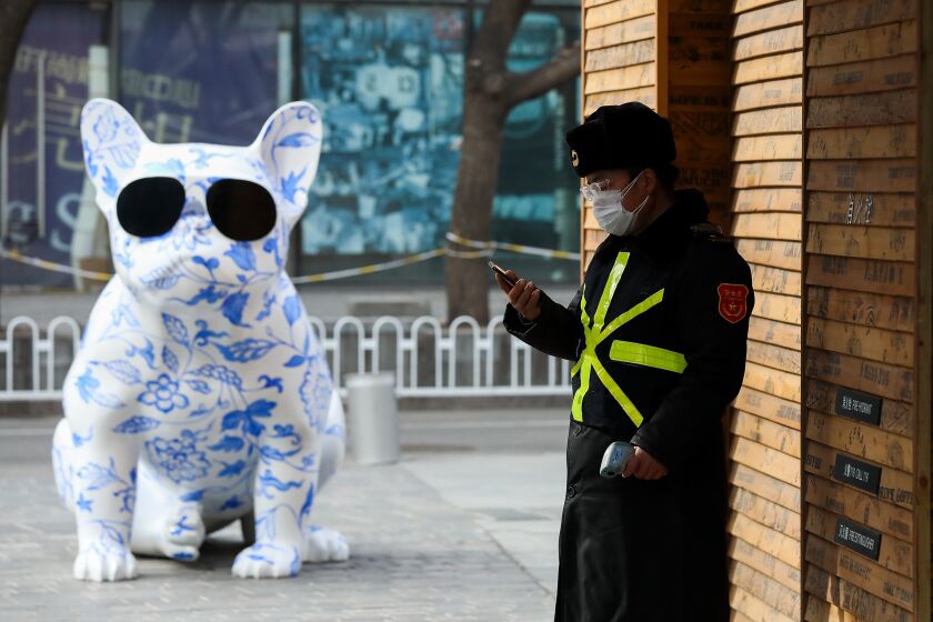 A security guard wears a protective mask outside an empty shopping mall in Beijing on Tuesday.