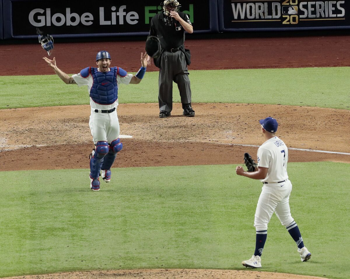 Austin Barnes throws his equipment in the air as he rushes to celebrate with Julio Urias after winning the World Series.