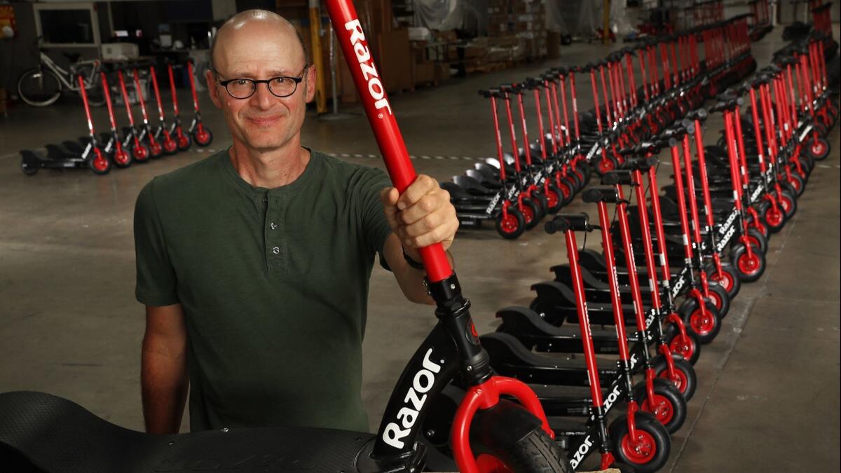 Carlton Calvin, the president and co-founder of Razor scooters, is photographed at Razor headquarters in Cerritos next to Razor share electric scooters, the newly launched dockless shared e-scooter program.