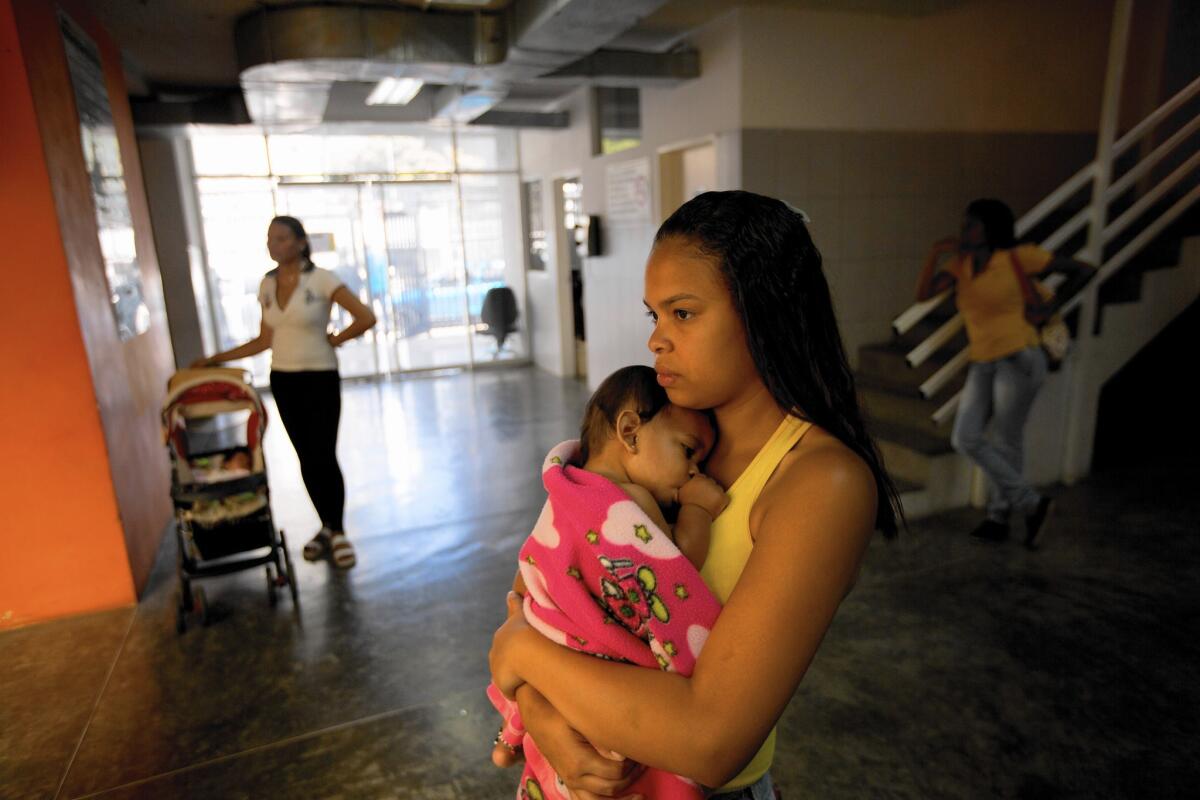 A woman holds her sick baby as she waits to see a doctor at a medical center in Caracas, Venezuela on Feb. 11.