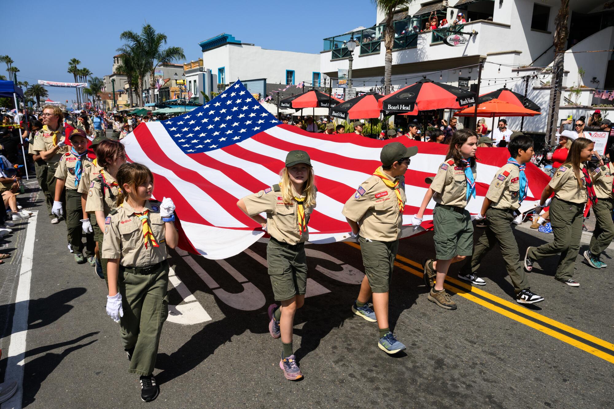 Ο όμιλος Scouting America έχει μια μεγάλη σημαία κατά τη διάρκεια μιας παρέλασης στις 4 Ιουλίου.