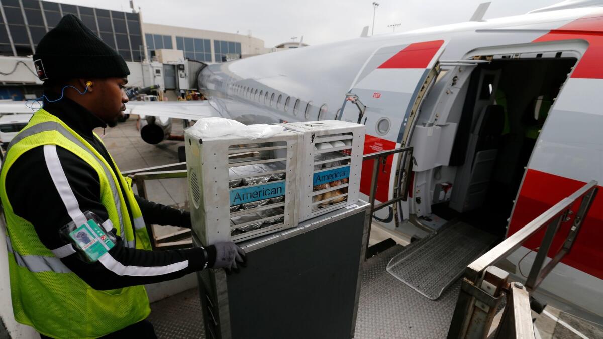 A food service worker loads food carts aboard an American Airlines flight to Orlando at Los Angeles International Airport. The airlines has returned to using Gate Gourmet, a catering company that was found to have listeria in its floor drain.