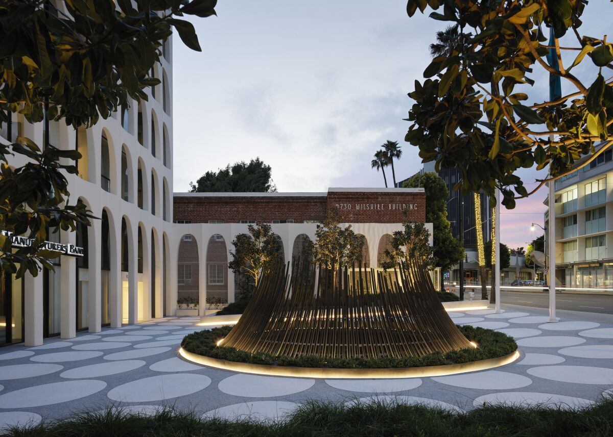 An outdoor view featuring a pattern of circles in the terrazzo and a metal sculpture resembling a fountain.