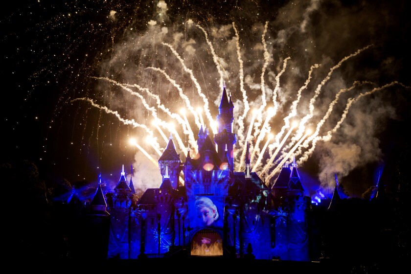 Fireworks burst above Sleeping Beauty Castle, bathed in blue light, at Disneylland on May 21, 2015.