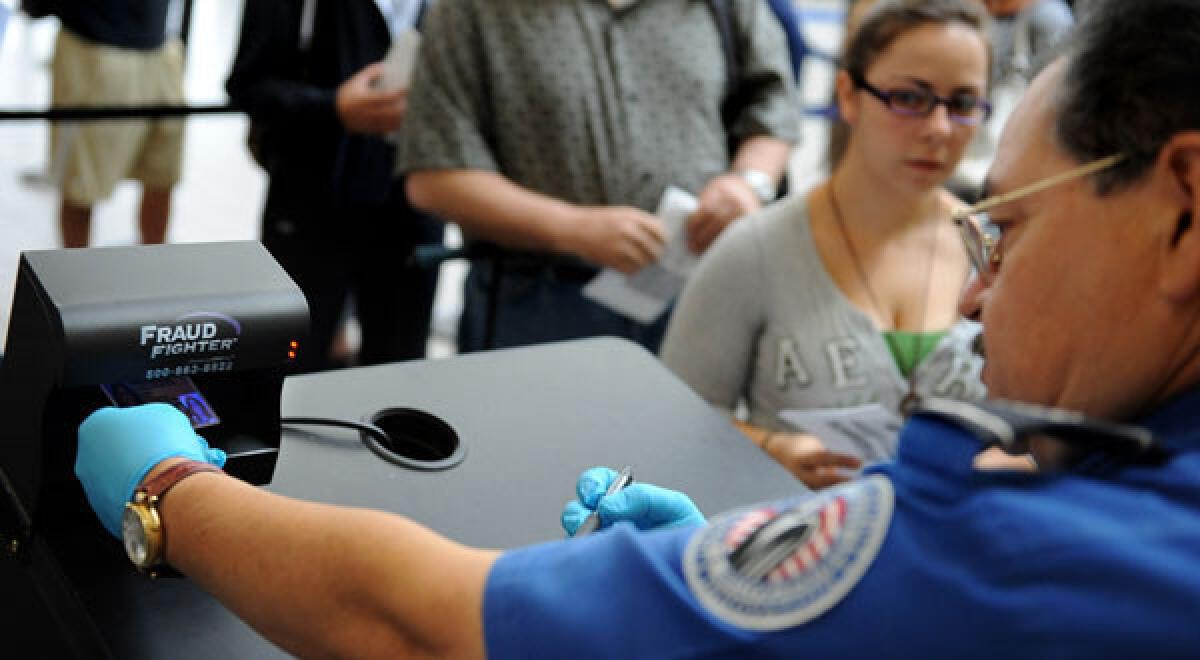 A TSA agent checks an id under a Fraud Fighter machine in Terminal 1 at LAX.