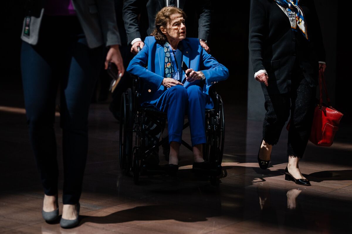 Sen. Dianne Feinstein sits in a wheelchair and is surrounded by staff