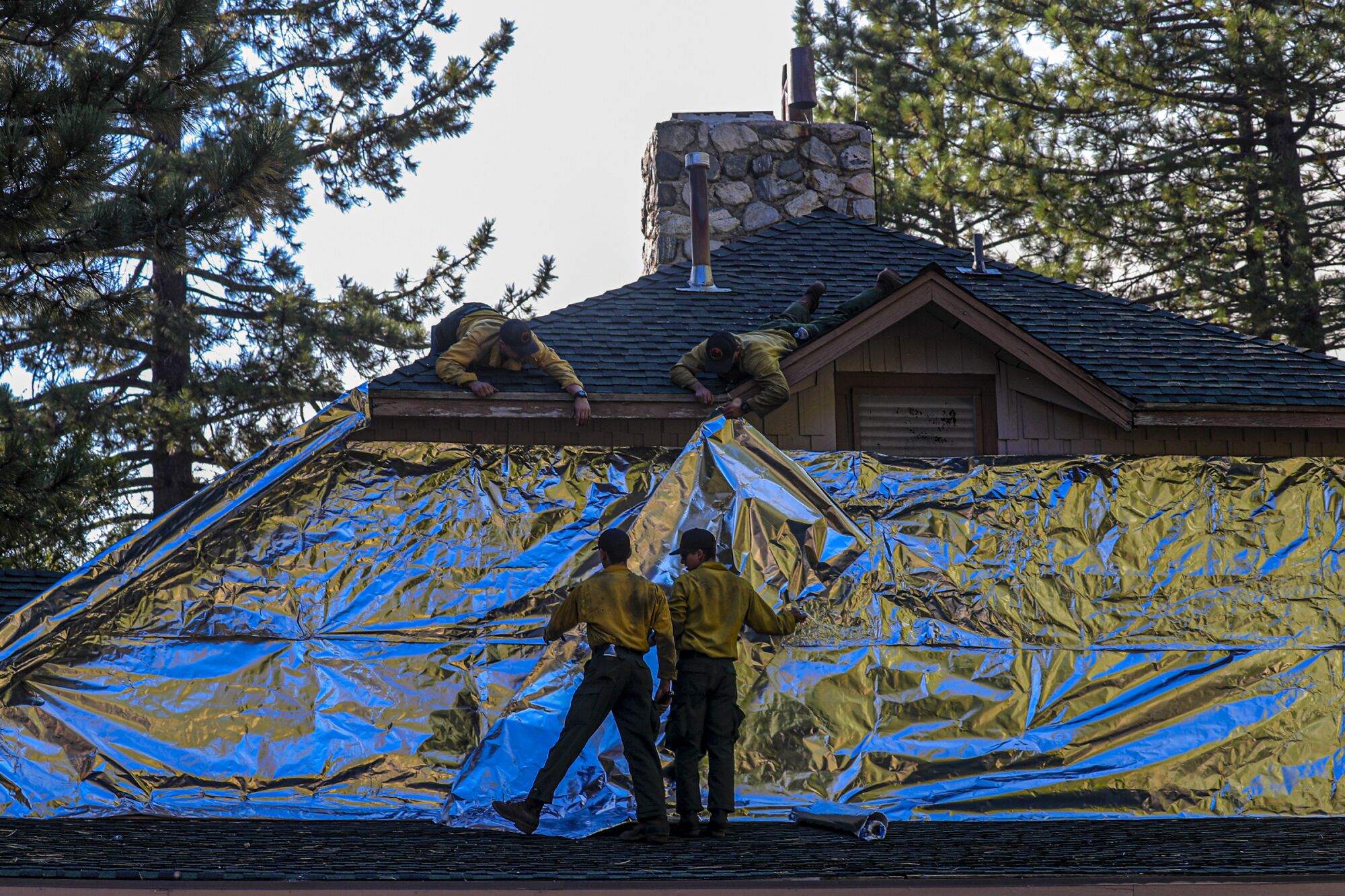 Bear Divide hot shots  wrap an  information center in a blanket to protect it from the Bobcat fire 