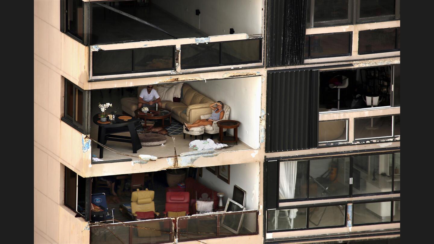 Two people sit in an apartment with a wall missing after Hurricane Maria passed over the island nearly a week ago.