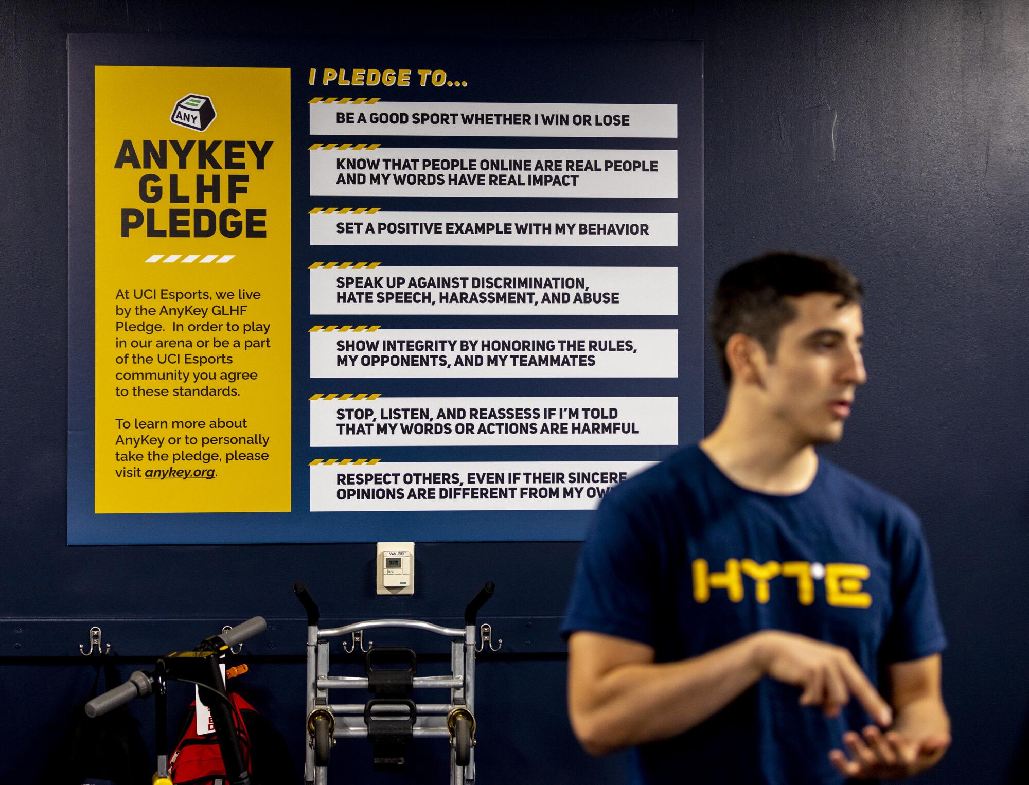 Phillip Rodriguez is shown with a poster of the UCI esports pledge while the team plays Overwatch 2.