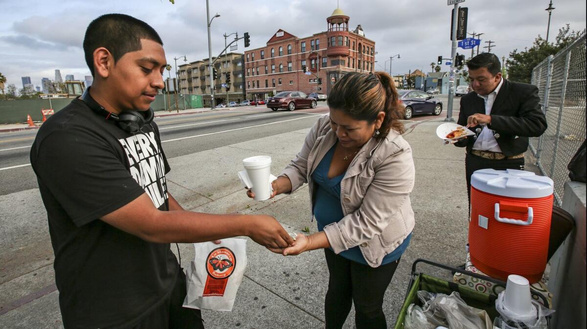 Eugenia Cruz sells tamales and a hot drink to 20-year-old Gonzalo Rossete in Boyle Heights on July 9, 2015.
