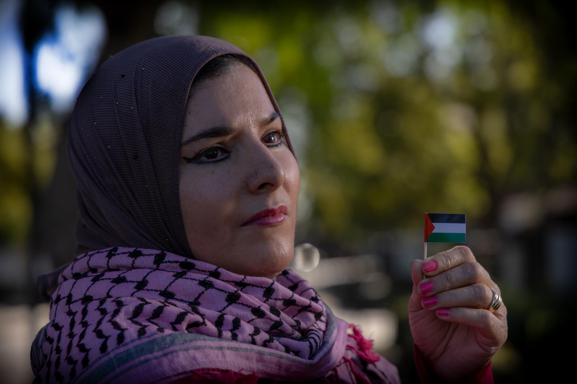 A woman holds up a miniature flag in one hand.