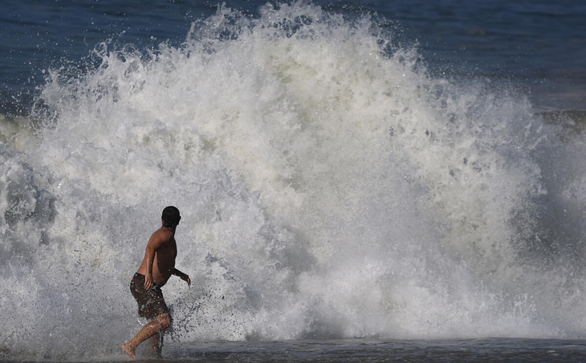 A man looks backmost arsenic a ample activity crashes connected the shoreline successful Laguna Beach