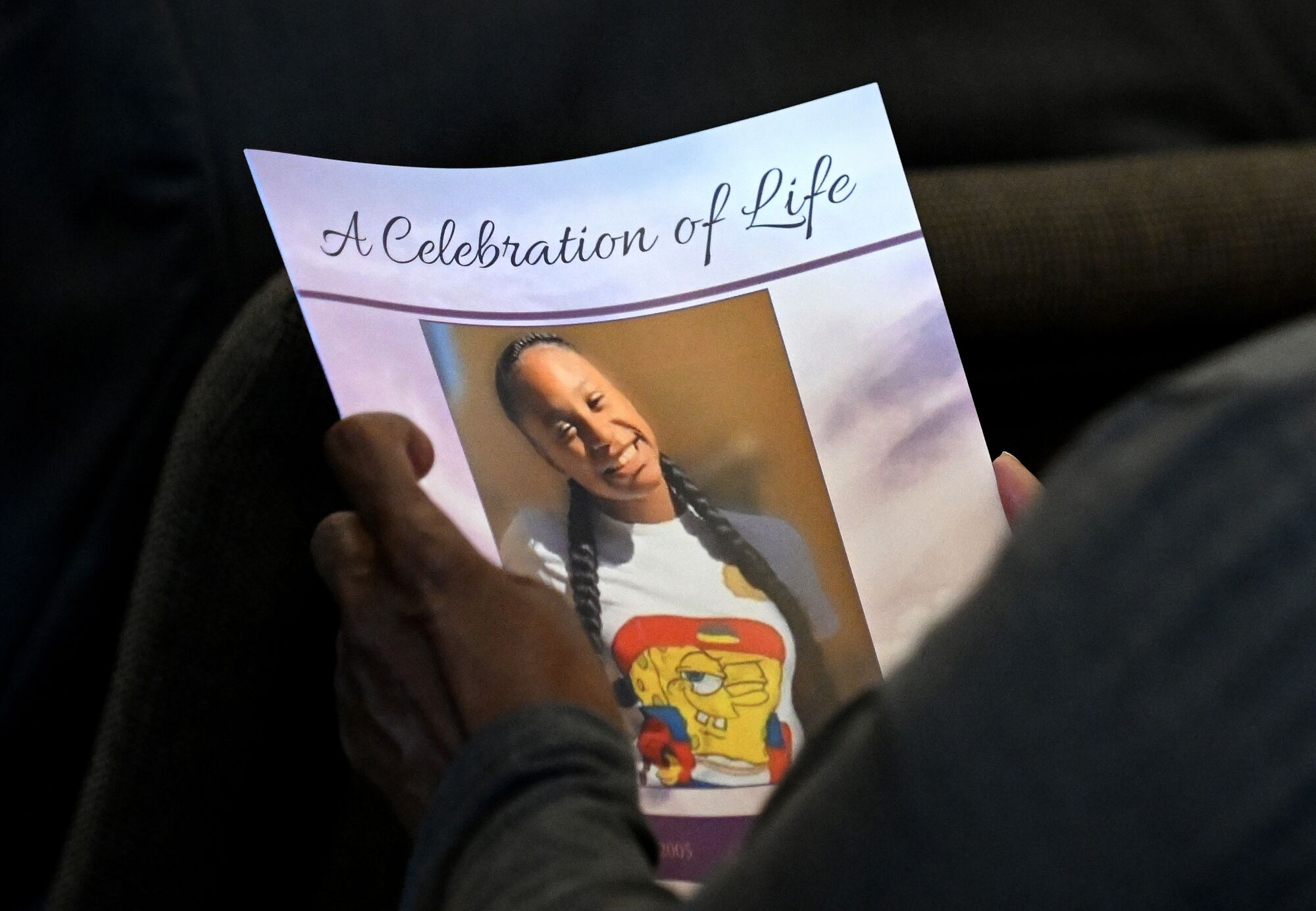 An image of Tioni Theus, seen smiling, on a funeral program. 
