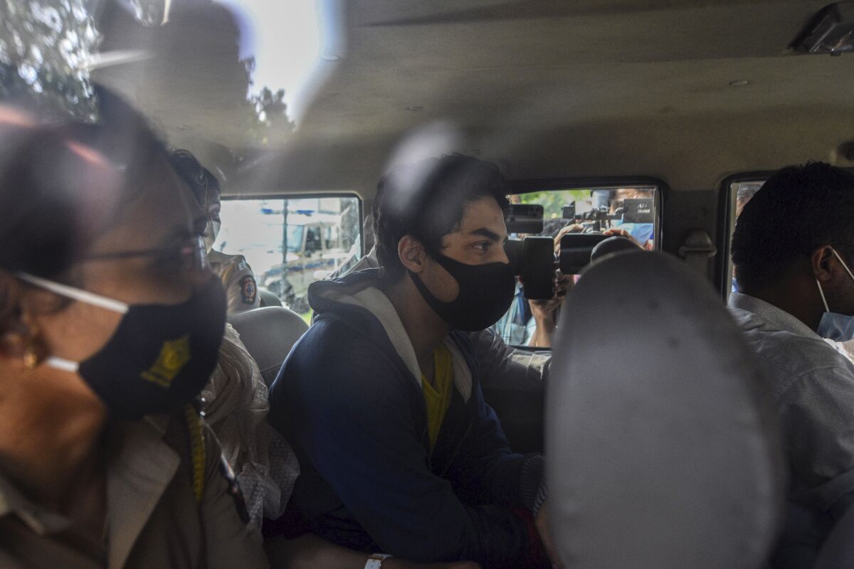 Bollywood actor Shah Rukh Khan’s son Aryan Khan, center, escorted by law enforcement officials sits inside a vehicle outside the Narcotics Control Bureau (NCB) to appear before a court in Mumbai, India, Monday, Oct.4, 2021. (AP Photo)
