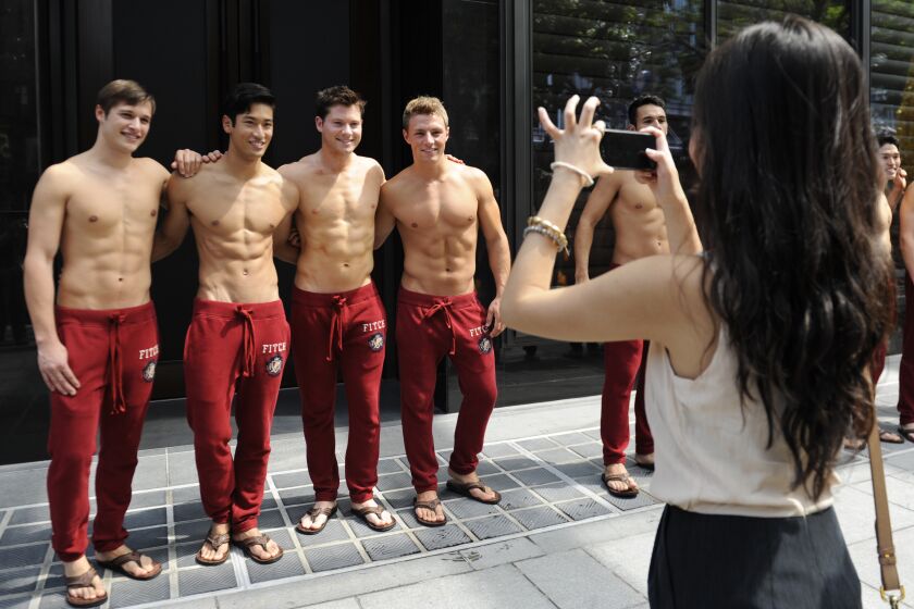 A passerby takes a picture of Abercrombie & Fitch (A&F) models outside the A&F store in Knightsbridge, a Singapore shopping mall on December 9, 2011. A&F's first Singapore store will open to the public on December 15. AFP PHOTO / SIMIN WANG (Photo credit should read SIMIN WANG/AFP/Getty Images) ORG XMIT: