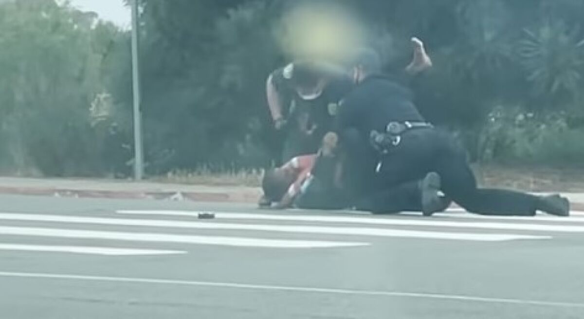 An image from a video shot by Nicole Bansal shows police officers tackling and punching Jesse Evans in La Jolla on May 12.