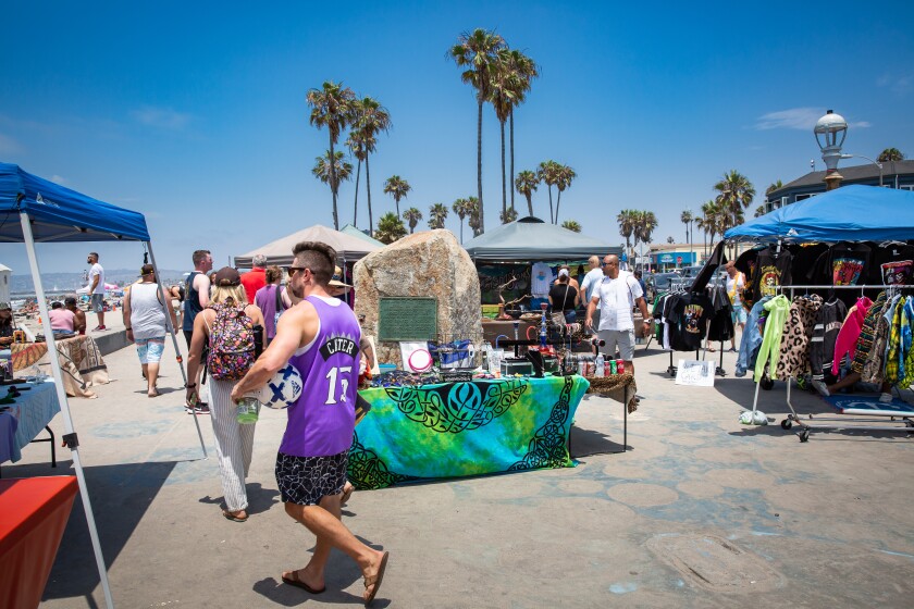 Visitors to Ocean Beach's Veterans Plaza walk among sidewalk vendors' displays.