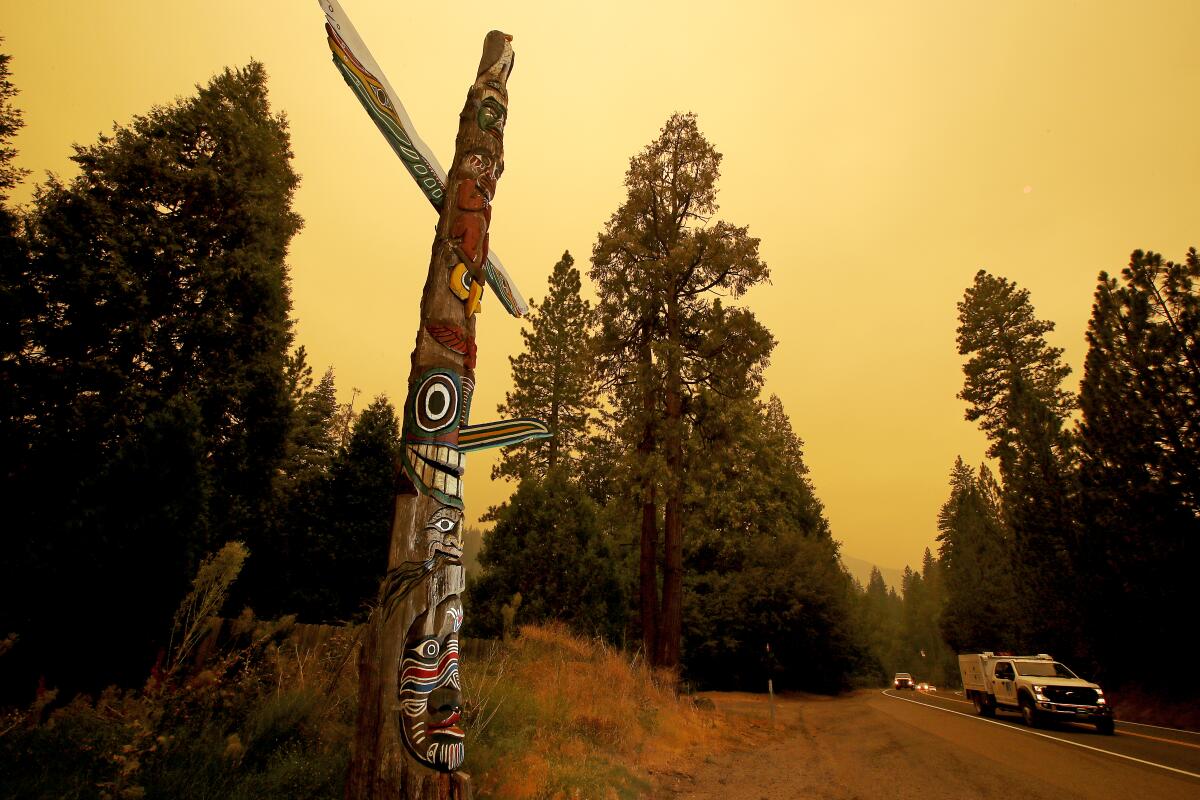 Motor traffic streams along Highway 50 against a smoke-filled sky near the community of Kyburz, Calif.