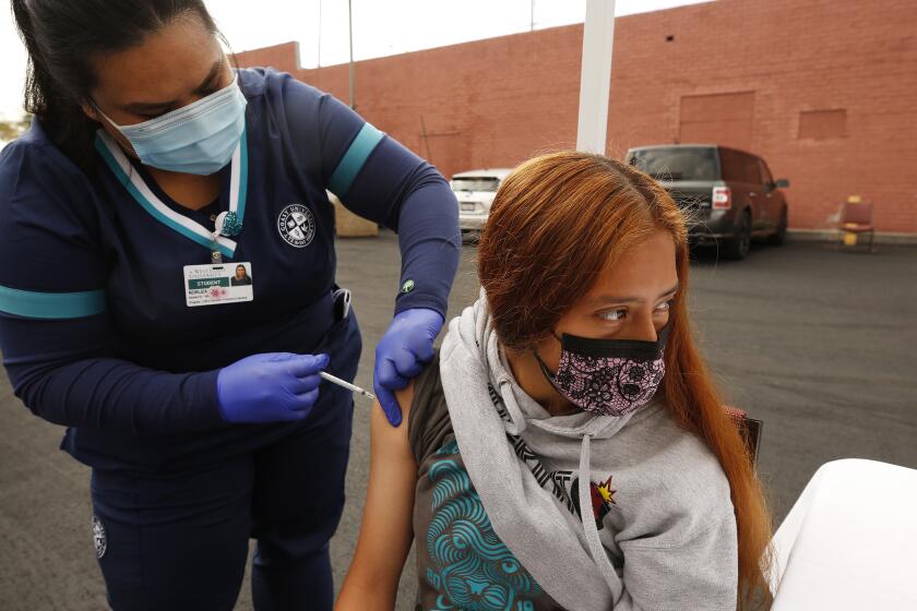 LOS ANGELES, CA - APRIL 20: Jamilette Mota, 17, receives her Pfizer Covid-19 vaccination from student registered nurse Josselyn Solano at a new, walk-up mobile COVID-19 clinic launched today to provide the Pfizer COVID-19 vaccine to underserved communities in Los Angeles. The walk-up clinic was presented by Councilmember Mark Ridley-Thomas in partnership with CHA Hollywood Presbyterian Medical Center (CHA HPMC) and the Southern California Eye Institute (SCEI). The Mobile Vaccine Clinic at 1819 S. Western Avenue will be open every Tuesday starting April 20 through May 25 providing free vaccines to community members who are eligible per LA County Department of Public Health (LAC DPH) vaccine distribution guidelines as they partnered with Charles R. Drew University of Medicine and Science to provide student volunteers for on-site registration allowing for walk-up appointments for community members and further ensuring vaccine access in our hardest-hit communities. Los Angeles on Tuesday, April 20, 2021 in Los Angeles, CA. (Al Seib / Los Angeles Times).