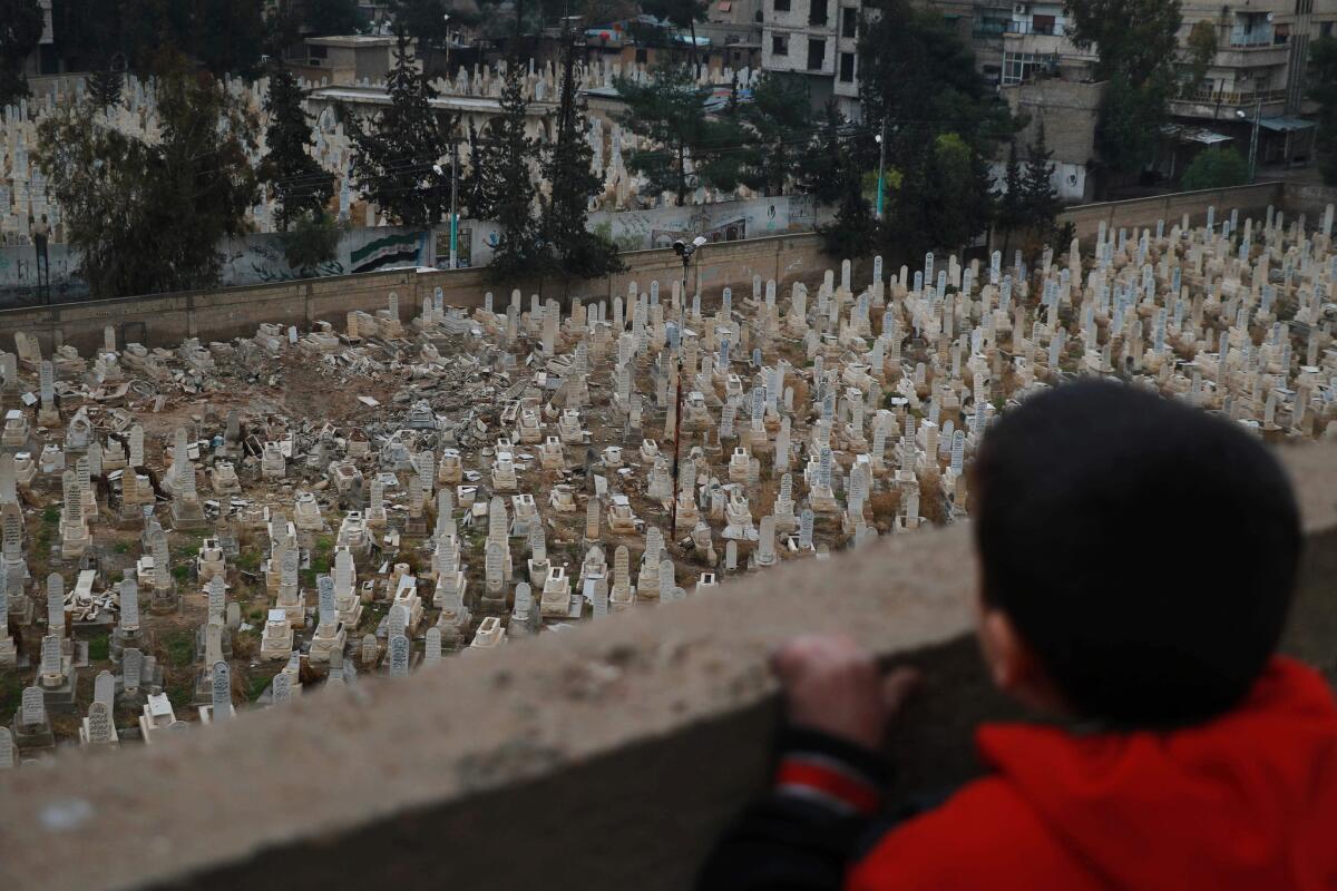 A Syrian boy looks over a cemetery in the rebel-controlled area of Arbeen on the outskirts of Damascus.