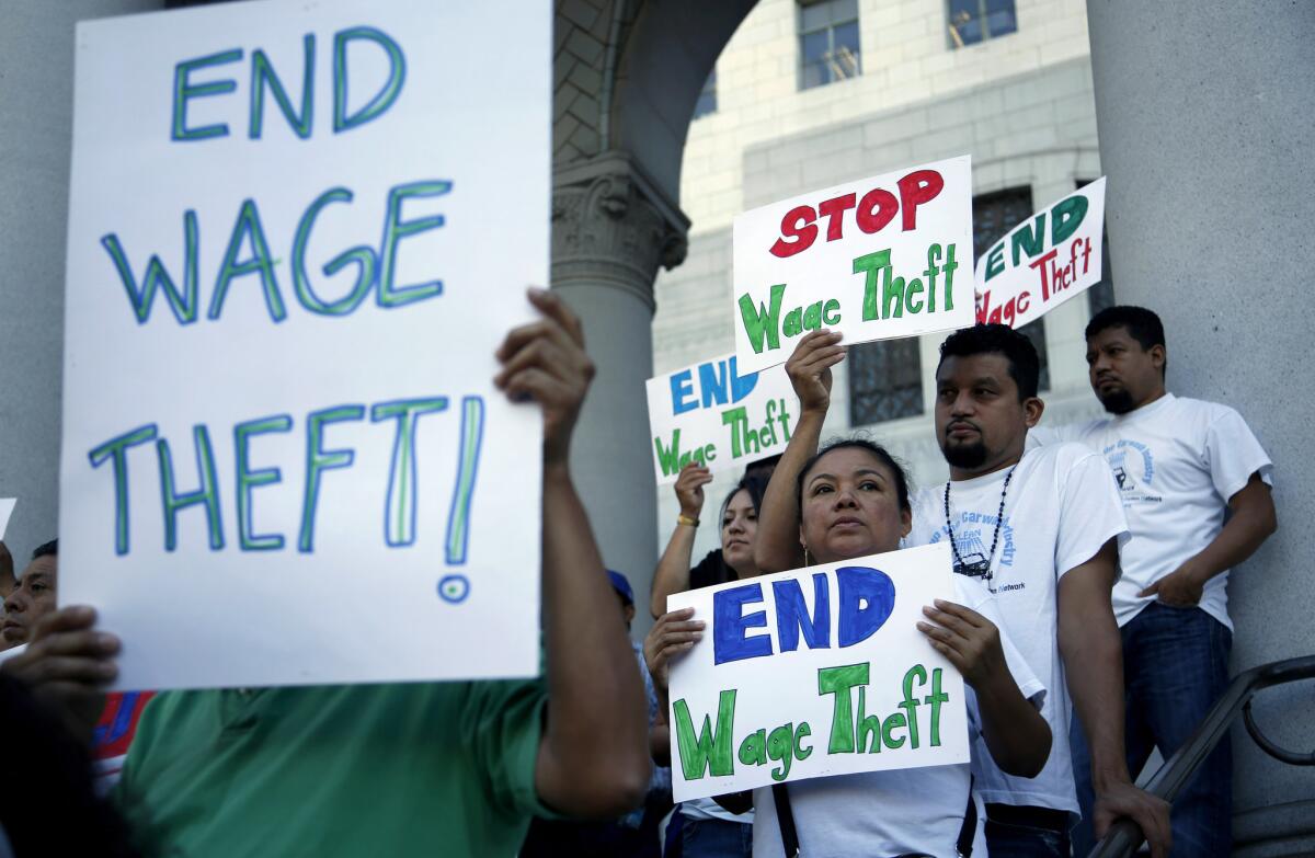 Workers appear at a news conference at Los Angeles City Hall last year to urge support for a boost in the minimum wage as well as wage-theft protections.