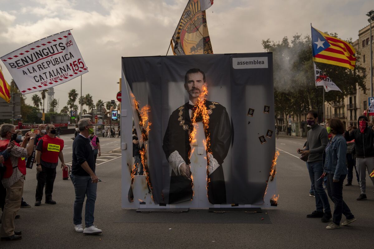Activists of Catalonia's pro-independence grassroots group, ANC, burn a portrait of Spain's King Felipe VI during a demonstration in Barcelona on Friday, Oct. 9, 2020. Several thousand Catalan separatists are protesting the visit of Spanish King Felipe VI and Prime Minister Pedro Sánchez to Barcelona amid continued tensions between the restive region and national authorities. (AP Photo/Emilio Morenatti)