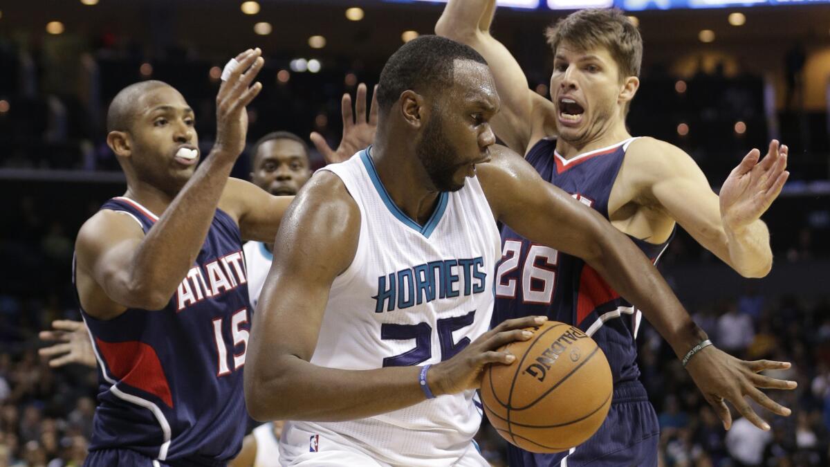 Charlotte's Al Jefferson, center, tries to drive past Atlanta's Al Horford, left, and Kyle Korver during the Hornets' 122-119 double-overtime victory Friday.