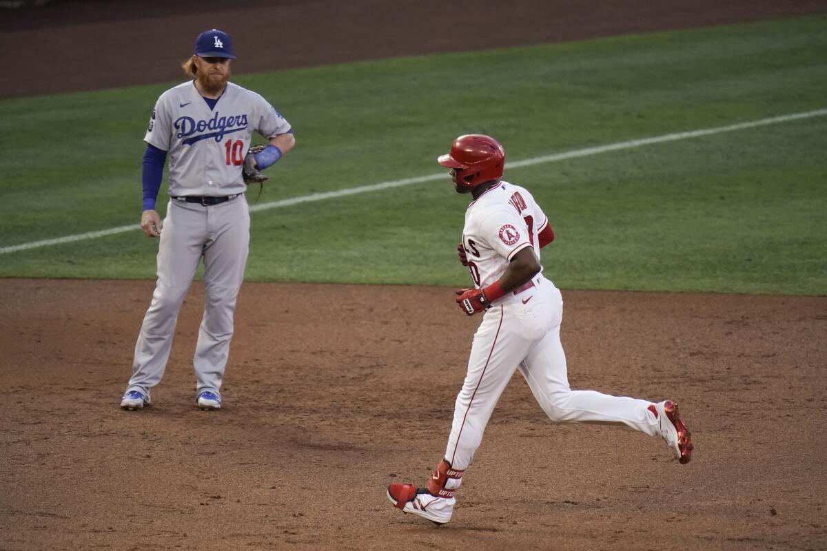 Angels batter Justin Upton rounds the bases in front of Dodgers third baseman Justin Turner after hitting a solo home run.