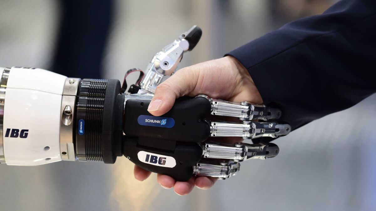 A person shakes hands with a robot during the Hanover Fair in Germany.