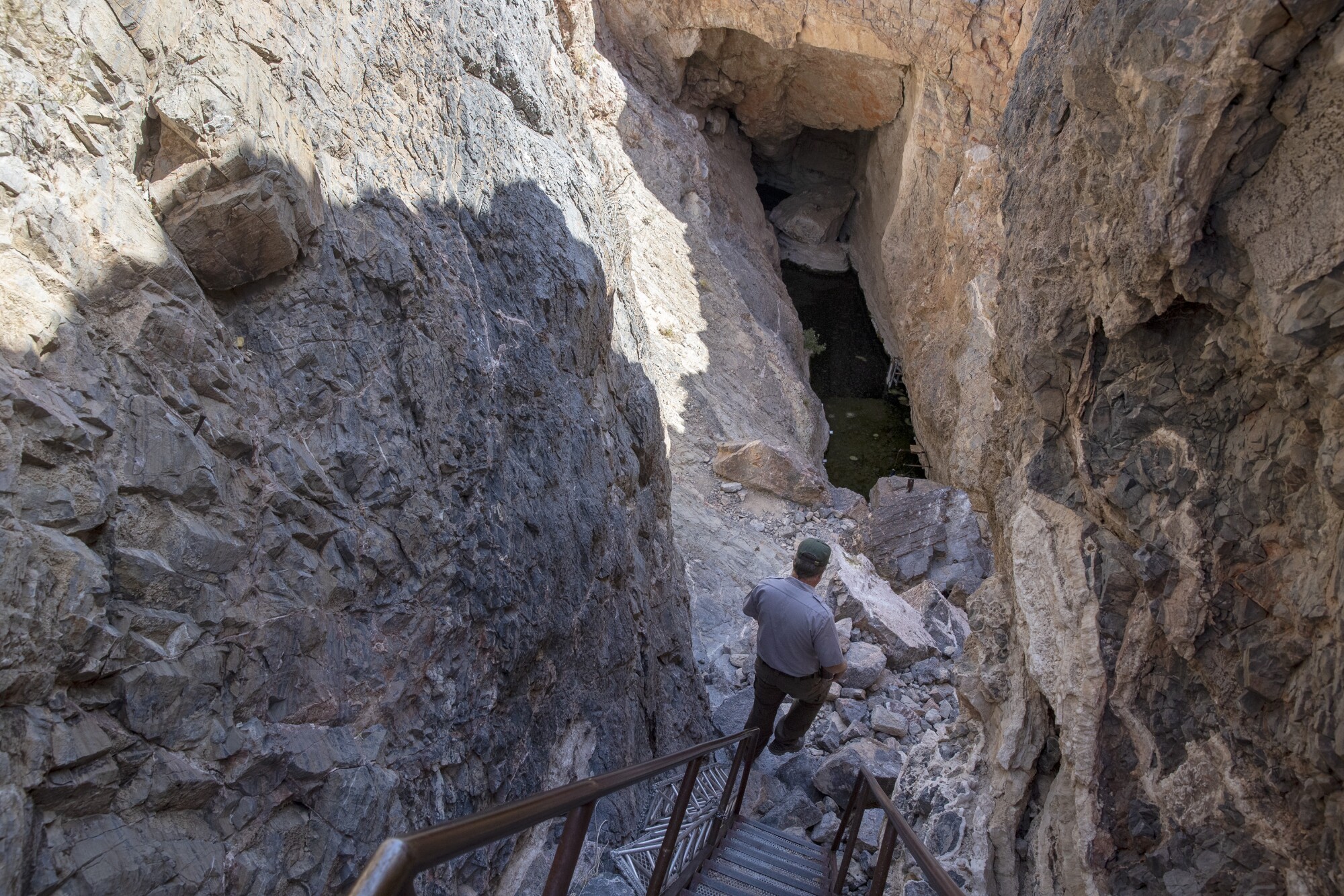 A man walks down steep stairs into a cave