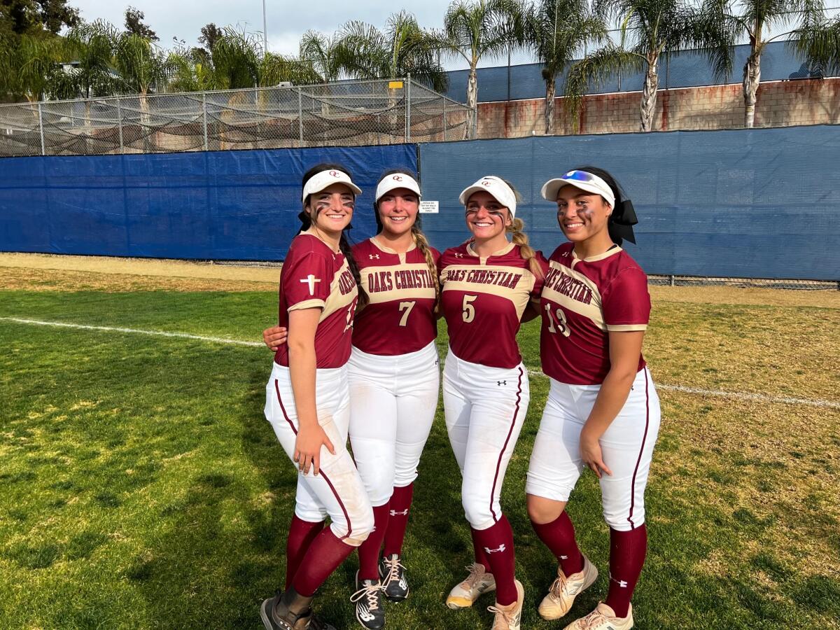 Softball players pose for a photo.