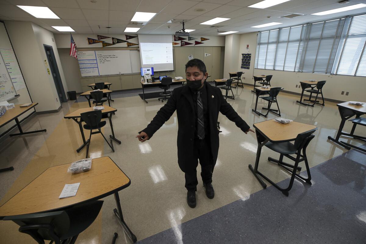 A teacher stands inside an empty classroom.