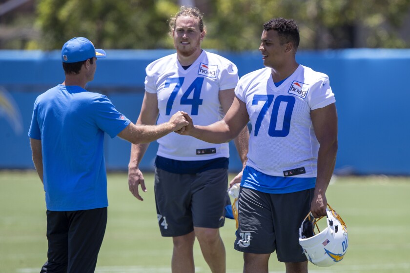 Chargers coach Brandon Staley greets offensive tackles Rashawn Slater (70) and  and Storm Norton during workouts.