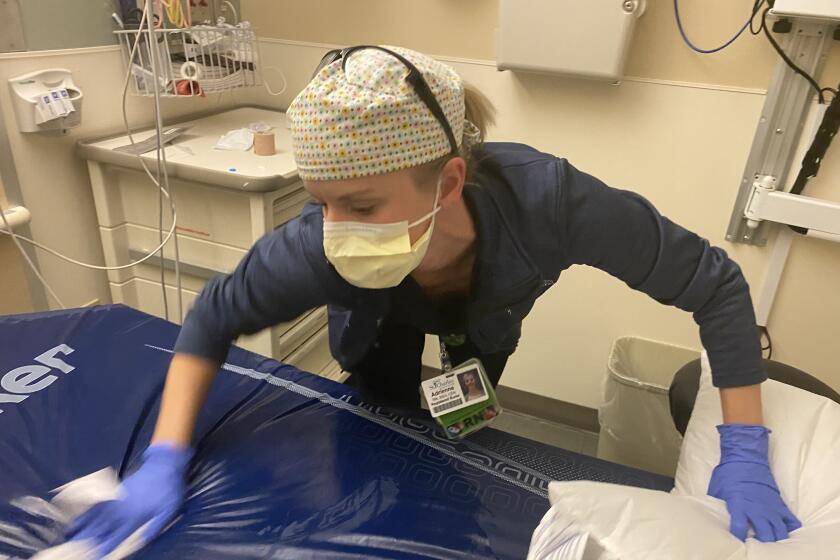 Nurse hurries to wipe down a mattress between patients.