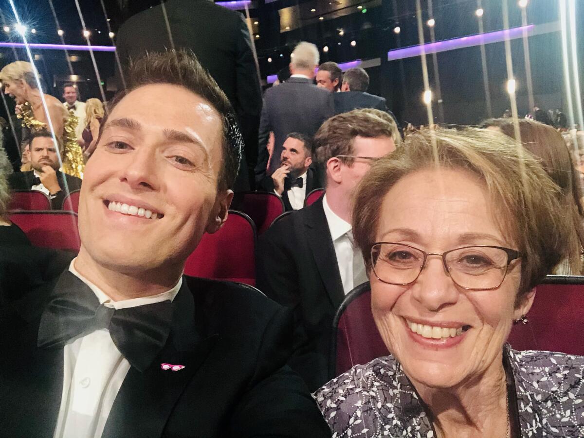 A smiling man in a tux next to a smiling woman at an awards show.