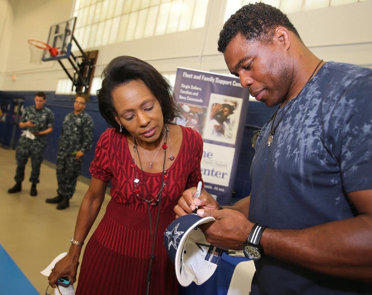 Former NFL player Herschel Walker autographs a Dallas Cowboys hat for Valerie Powell at Naval Support Activity Panama City in Panama City Beach, Fla., on June 4.