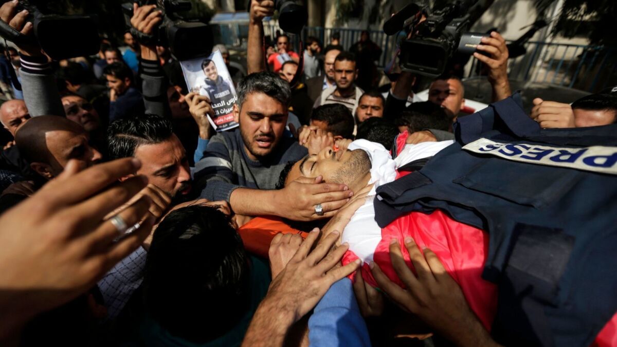 Journalists and other mourners carry the body of Palestinian journalist Yasser Murtaja during his funeral in Gaza City on April 7, 2018. Murtaja, a photographer with Gaza's Ain Media agency, was among those shot dead during Friday's clash between Israeli forces and Palestinians.