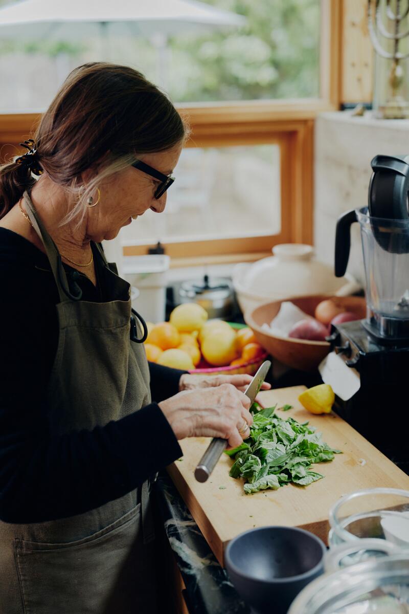 A woman in a kitchen prepping herbs for soup