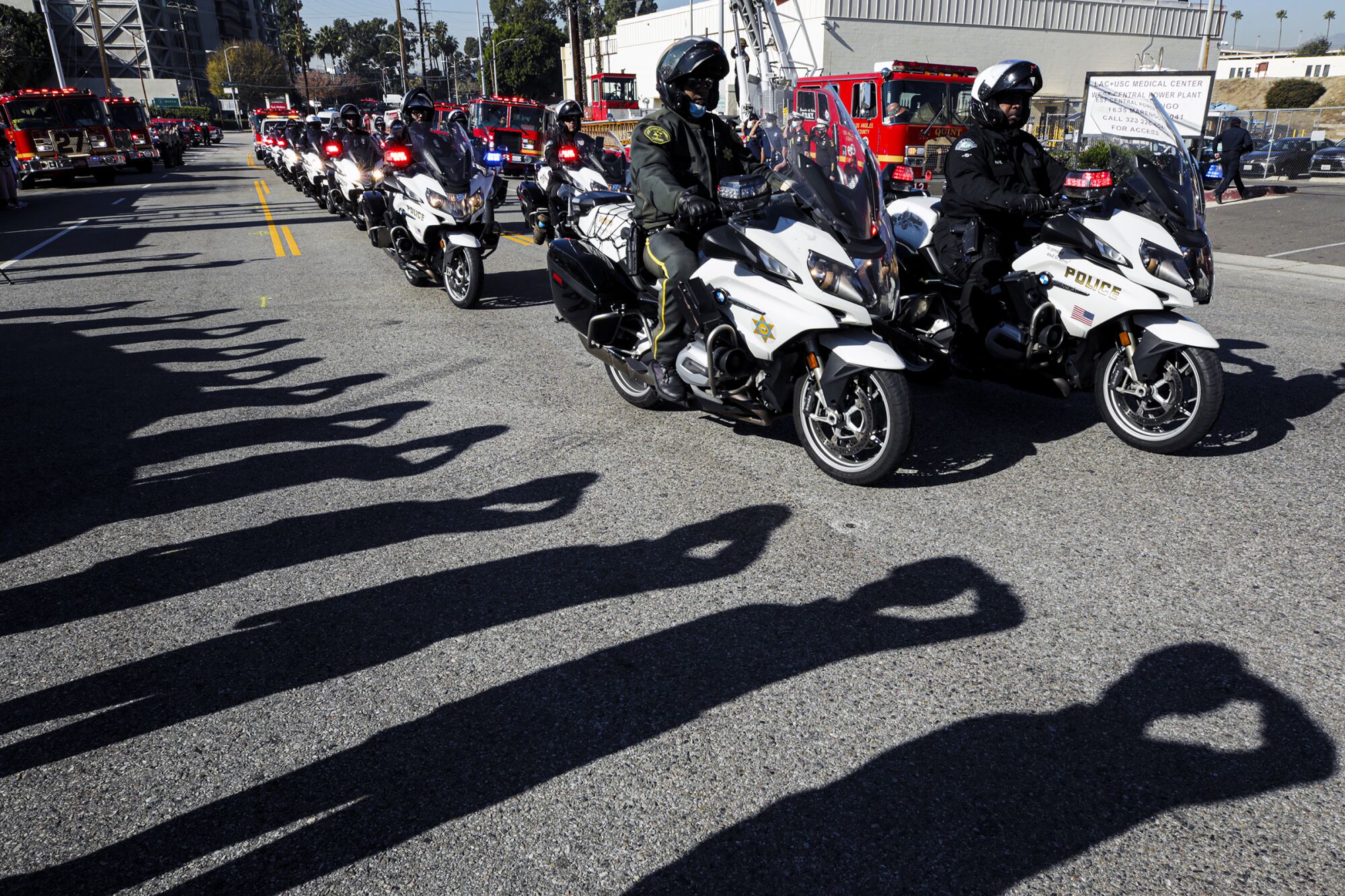A line of police officers on motorcycles drive down a street
